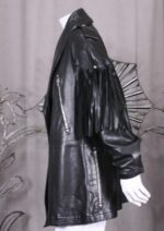 Women's black leather moto coat featuring fringe accents on sleeves and back for an edgy, vintage look.
