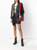 Edgy black leather jacket with leopard patch, shoulder studs, and red zip pocket, blending punk and glam rock styles.