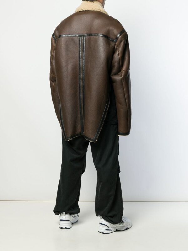 Casual street style featuring oversized brown shearling leather coat layered over black clothing with white sneakers.