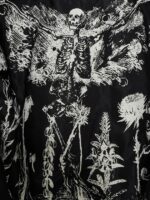 Rebellious black leather jacket with skull pattern lining, asymmetrical zip closure, and shiny silver buttons and zippers.