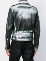 Person wearing a black and silver gradient leather jacket with asymmetrical zippers and structured collar, paired with black pants for an edgy look.