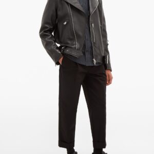 A person wearing a black leather jacket, dark pants, and black shoes, exuding a stylish and edgy vibe. The outfit blends casual and chic elements.