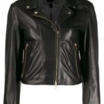 Black leather biker jacket featuring a gold zipper closure and pocket accents, with a chain detail inside. The style is edgy and sleek.