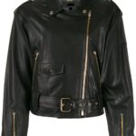 A person wearing a black leather biker jacket with zippers and silver hardware over a black turtleneck. The outfit is paired with a black and white patterned skirt. The tone is stylish and edgy.