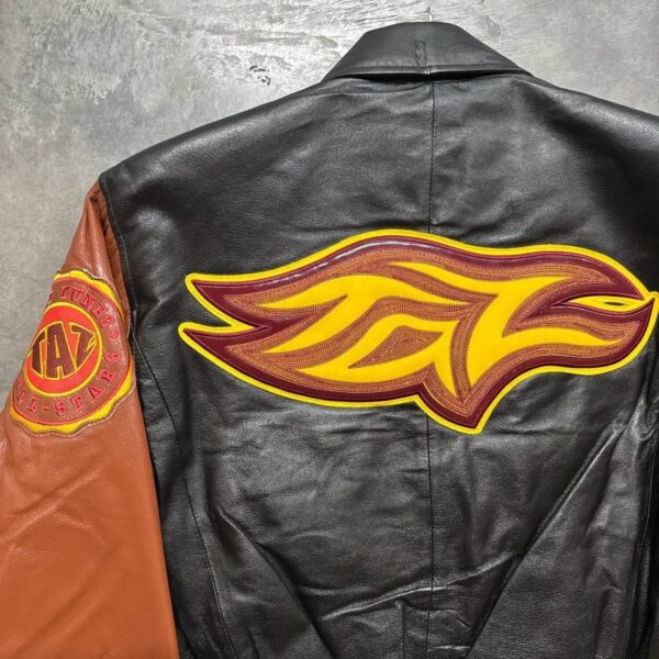 A closeup photo of Tasmanian Devil leather jacket with a large yellow and red flame logo on the back and a circular patch on the left sleeve.