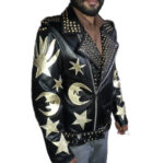 Men’s edgy black leather punk biker jacket with bold gold crescent moons, stars, and hand symbols; side angle showing studded details and belted waist.