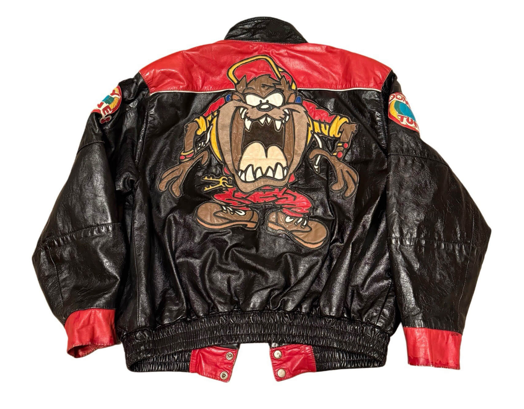 Vintage-Looney-Tunes-TAZ-Cartoon-Leather-Jacket-1 Back view of Vintage Looney Tunes TAZ Cartoon Leather Jacket featuring large TAZ cartoon patch and Looney Tunes logos on both arms.