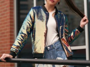 Women wearing cropped bomber jacket with white top and blue jeans outdoors