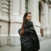 Women in black coat glancing back on a quiet city street.