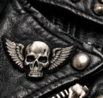 Skull wing metal badge on black leather jacket close up