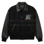 Front view of The Flintstones Bedrock N Roll Black Varsity Jacket featuring leather sleeves, collar, and pocket trim and colorful cartoon dinosaur patch on the left chest.