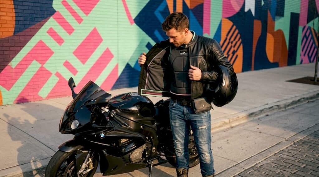 Motorcyclist checks padding in jacket outdoors