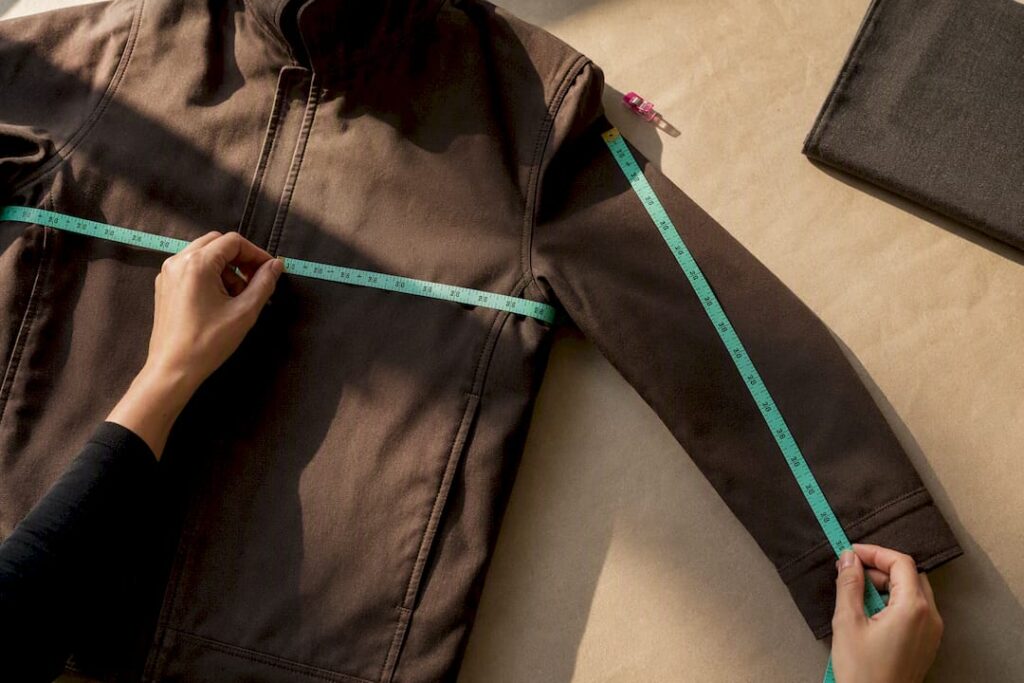 Hands measuring jacket dimensions with tape
