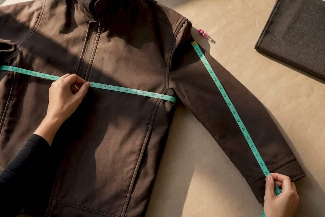 Hands measuring jacket dimensions with tape